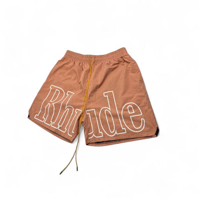 MASTERPIECE brown quick-dry swim shorts with oversized white Rhude logo and yellow drawstring.