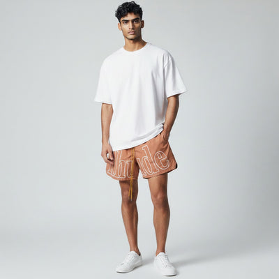 MASTERPIECE brown quick-dry swim shorts with oversized white Rhude logo and yellow drawstring.