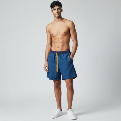 MASTERPIECE Rhude blue panel swim shorts with yellow drawstring and embroidered logo. Lightweight, quick-drying fabric with mesh lining.