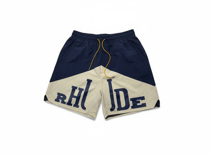 MASTERPIECE navy and cream color-blocked swim shorts with large RHUDE logo and yellow drawstring.