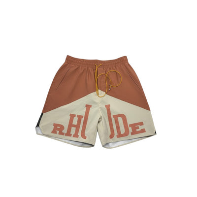 MASTERPIECE Rhude panel logo swim shorts in rust brown and cream with oversized branding and yellow drawstring.