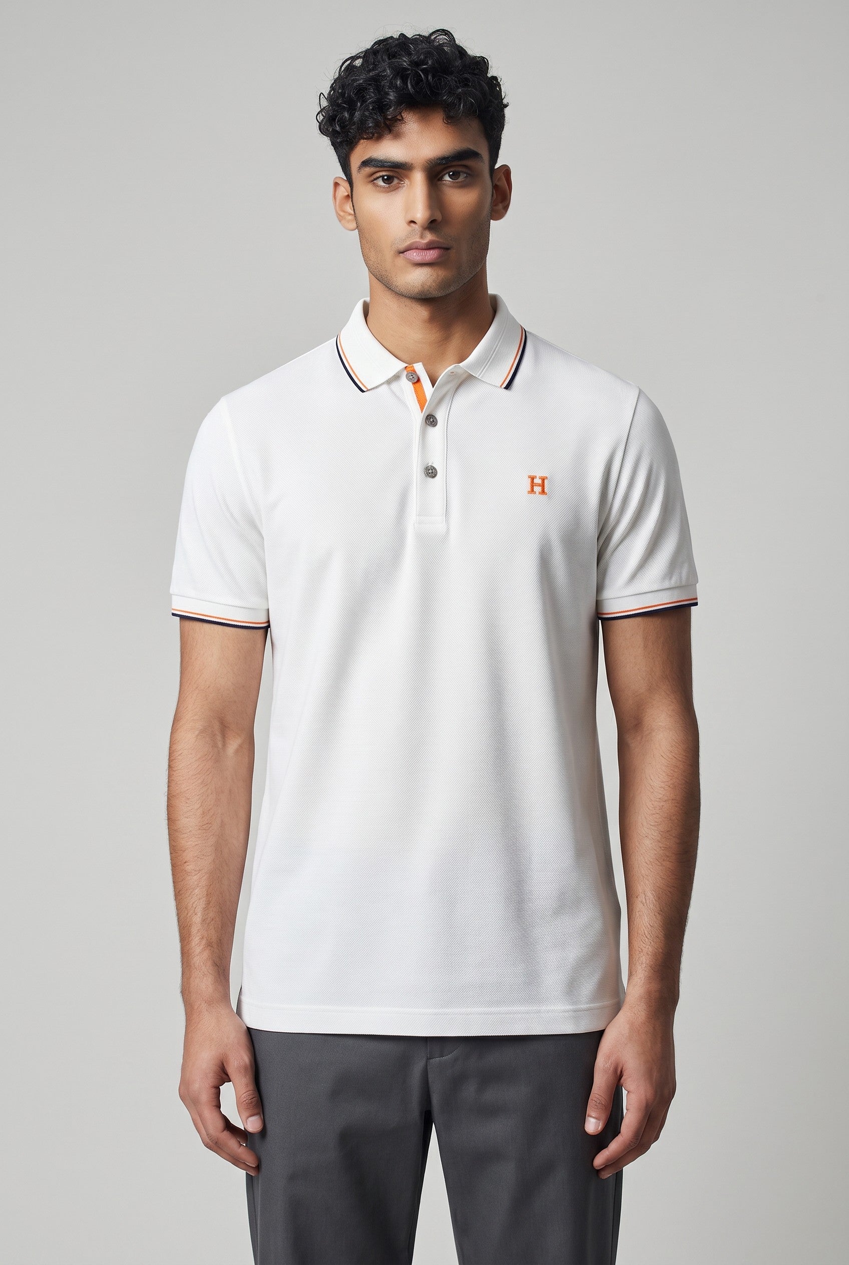 MASTERPIECE white textured polo shirt with orange embroidered H logo and contrast stitching on collar and cuffs.